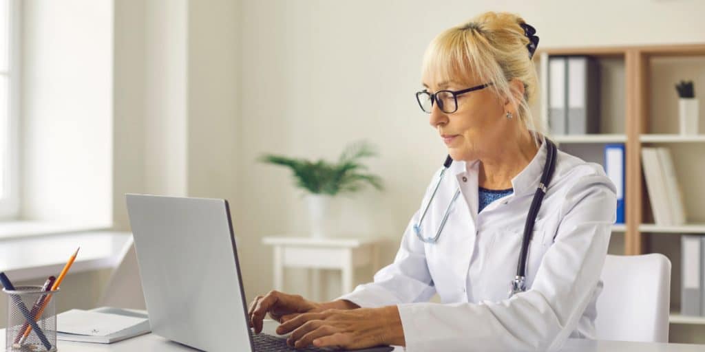 Doctor Typing on Laptop At Desk