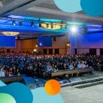 Man on stage overlooking a full crowd at a healthcare conference